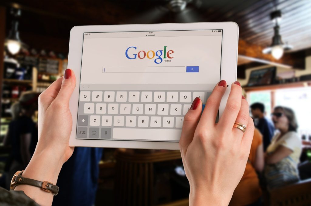 person holding tablet with google search on screen